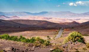 The road goes towards a desert mountain landscape in Morocco