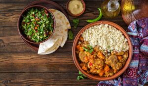 Traditional tajine dishes, couscous and fresh salad on rustic wooden table