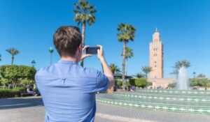 Man takes a smartphone photo of the Koutoubia Mosque in Marrakech, Morocco