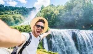 Handsome tourist visiting national park taking selfie picture in front of waterfall